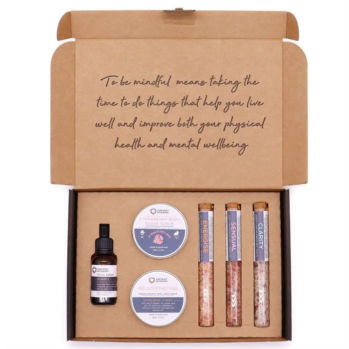 A brown cardboard serenity essential self care kit box with facial serum, sugar scrubs, and colored salt tubes