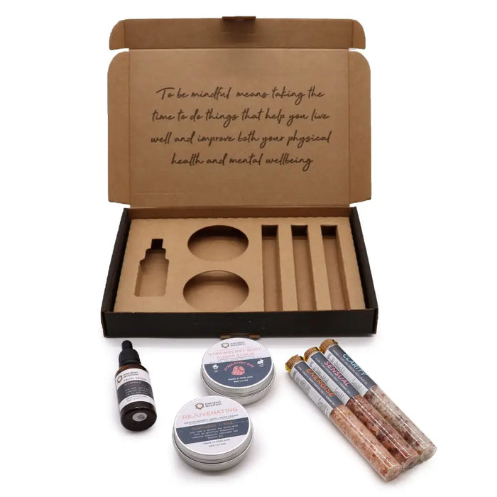 A brown cardboard serenity essential self care kit with a mindfulness message and wellness tins and tubes inside