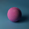 A round textured bath bomb with vibrant pink to deep purple gradient from the set of 3 bath bombs blackberry