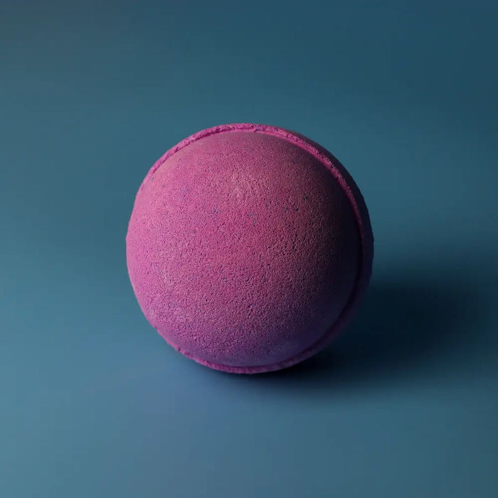 A round textured bath bomb with vibrant pink to deep purple gradient from the set of 3 bath bombs blackberry
