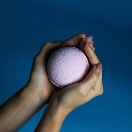 A soft lavender bath bomb with a textured surface from a set of 3 bubblegum bath bombs