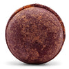 A round textured bath bomb in maroon and brown speckles from a set of 3 bath bombs chocolate and orange