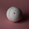 A white round bath bomb with red speckles from the set of 3 bath bombs coconut dream collection