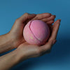 A soft pink round bath bomb with a subtle crack from the set of 3 bath bombs five for her collection