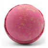A round pink bath bomb with a textured surface and yellow speckles from a set of 3 bath bombs five for her