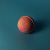 A round textured bath bomb with pink and orange gradient colors from the set of 3 bath bombs five for her