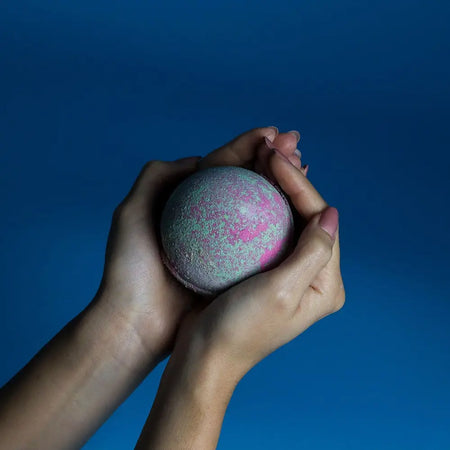 A spherical glittery bath bomb with pink and silver hues from a set of 3 fruity rhubarb bath bombs