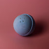 A matte blue bath bomb with dried herbs embedded from a set of 3 bath bombs lavender and seeds