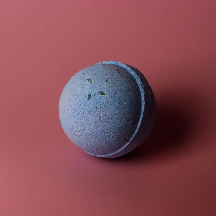 A matte blue bath bomb with dried herbs embedded from a set of 3 bath bombs lavender and seeds