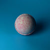 A spherical pink and white textured bath bomb from the party girl set of 3 bath bombs