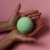 A soft mint green bath bomb with a textured surface held in hands from a set of 3 tea tree bath bombs