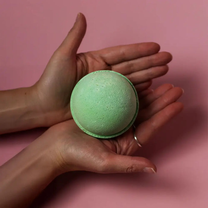 A soft mint green bath bomb with a textured surface held in hands from a set of 3 tea tree bath bombs