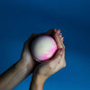 A round textured bath bomb in soft pink and creamy white colors from a pink lemonade bath bombs set of 3