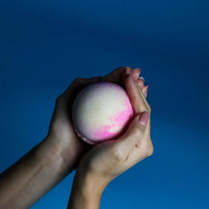 A round textured bath bomb in soft pink and creamy white colors from a pink lemonade bath bombs set of 3