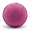 A vibrant magenta bath bomb with dark speckles in a set of 3 bath bombs featuring rose petals and texture