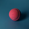 A matte pink bath bomb with a textured surface from a set of 3 bath bombs scented with rose petals