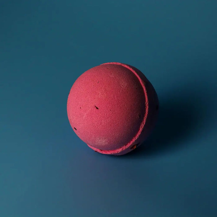 A matte pink bath bomb with a textured surface from a set of 3 bath bombs scented with rose petals
