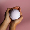 A lavender round bath bomb with textured surface and subtle speckles in a set of 3 bath bombs sweet fennel and jojoba