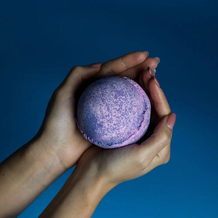 A spherical speckled bath bomb with purple and pink gradient colors from the set of 3 yorkshire violet bath bombs