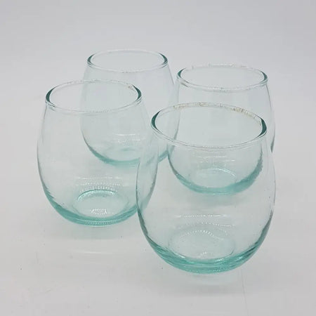 Set of four clear teal tinted stemless tumblers made from hand blown recycled glass with textured rims
