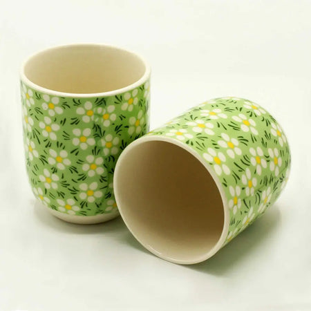 Green daisy ceramic toothbrush holder with white daisies and black stems as part of a small herbal tea cup set
