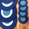 Blue felt coasters with concentric circles paired with jute rope placemats featuring evil eye design in blue and white