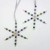 Iridescent snowflake ornaments with silver accents and rainbow beads hanging by ribbons in two designs
