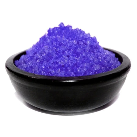 A black ceramic bowl holds vibrant purple blackberry simmering granules with a crystalline texture