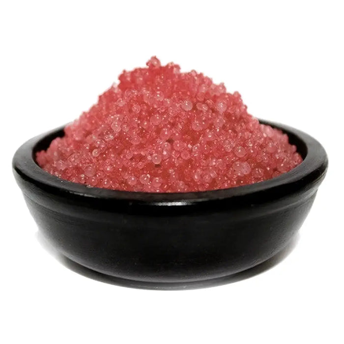 A mound of translucent pink simmering granules in a smooth black ceramic bowl for christmas pudding scent