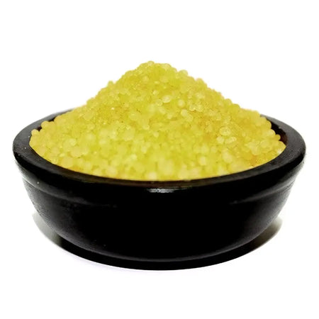 A mound of coarse translucent yellow citronella simmering granules sits in a smooth black ceramic bowl