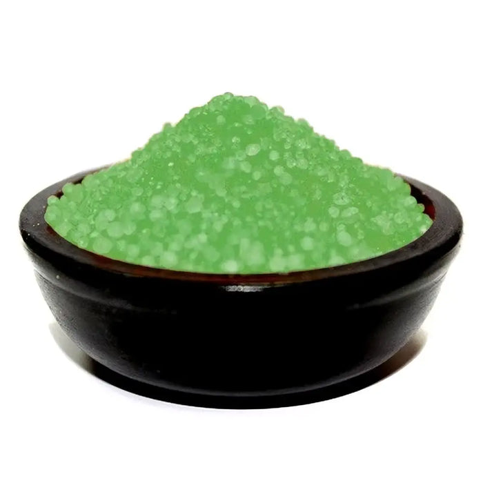 A glossy black bowl holding vibrant green translucent simmering granules in holly berry and mistletoe scent