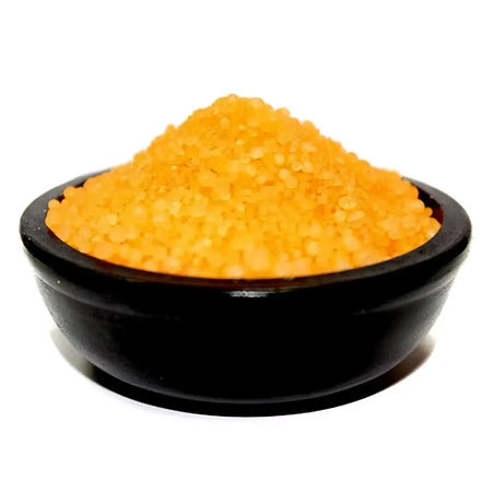 A black ceramic bowl filled with vibrant orange coarse simmering granules called honeysuckle