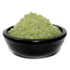 A mound of translucent green simmering granules in a matte black ceramic bowl for sandalwood scent baths