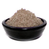 A black ceramic bowl holds a mound of translucent light brown simmering granules sandalwood crystals