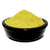 A mound of coarse yellow vanilla simmering granules bath salts in a smooth black ceramic bowl