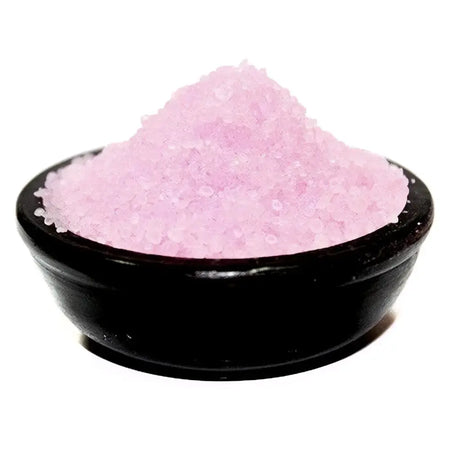 A mound of pink translucent salt simmering granules in a glossy black ceramic bowl for vanilla flavoring
