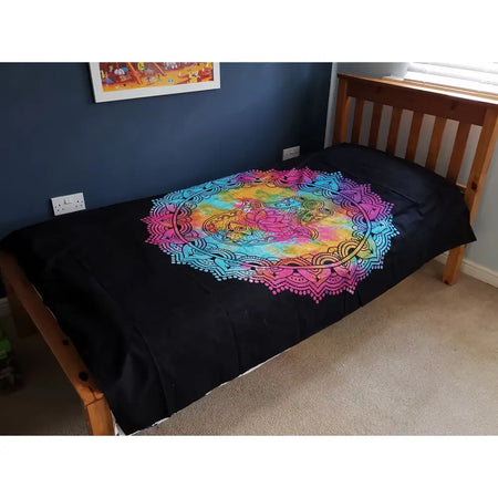 Black cotton bedspread with vibrant rainbow mandala design featuring floral motifs used as bedspread or wall hanging