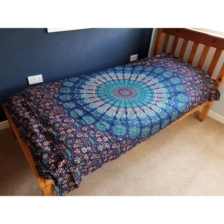 A single cotton bedspread in blue and teal with mandala floral patterns draped on a wooden frame for wall hanging