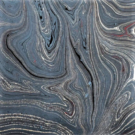 Single sheet handmade marbled gift wrap with swirling dark gray black and silver patterns and green gold accents