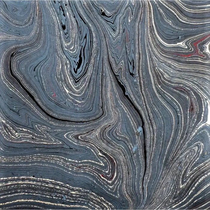 Single sheet handmade marbled gift wrap with swirling dark gray black and silver patterns and green gold accents