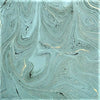 A single sheet handmade marbled gift wrap with smooth teal gray swirls and subtle green gold tones