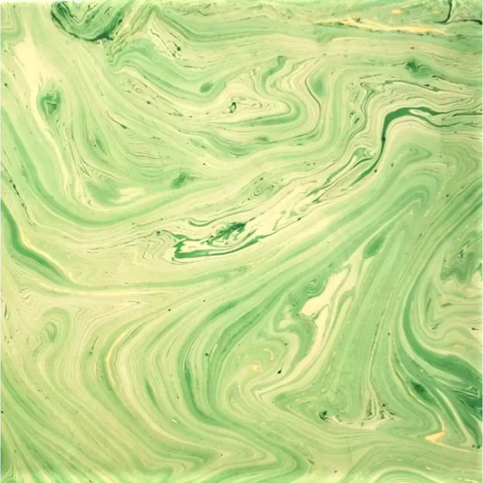 A single sheet handmade marbled gift wrap in green gold with a swirling cream marble pattern