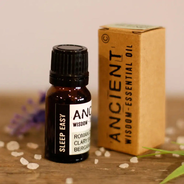 A small amber glass bottle with black cap labeled ancient wisdom sleep easy essential oil blend for relaxation