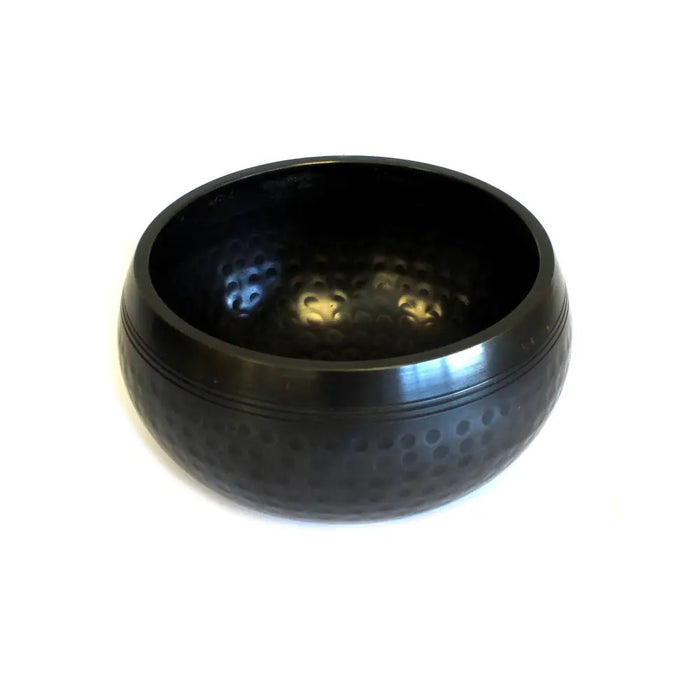 Small black beaten brass singing bowl with hammered texture and smooth reflective rim for meditation and sound healing