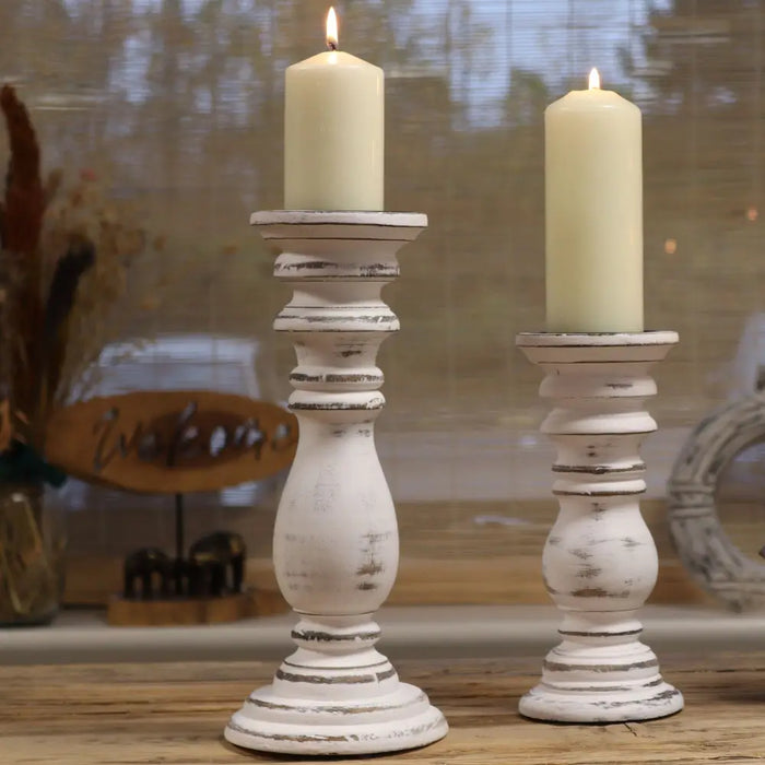 Small whitewashed mango wood candle stand with distressed finish holding cream-colored candles