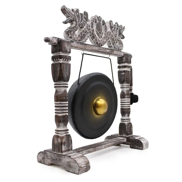 A small black healing gong with a golden center on an ornate wooden stand with carved dragon details