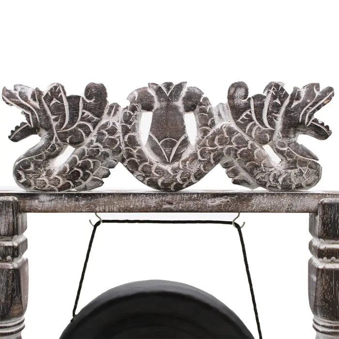 Small healing gong on black stand with rustic wooden dragon design and weathered gray finish suspended by black cords