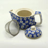 Small herbal teapot in blue ceramic with white and yellow daisy pattern and cream-colored handle and interior
