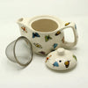 Cream-colored ceramic small herbal teapot decorated with multicolored butterfly illustrations for herbal tea cups