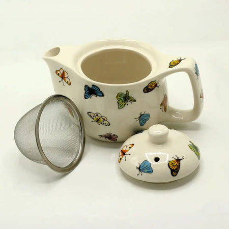 Cream-colored ceramic small herbal teapot decorated with multicolored butterfly illustrations for herbal tea cups